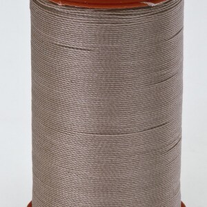 Puede incluir: Una bobina de hilo Coats Extra Strong para tapicería, de color marrón claro. La bobina está etiquetada "Coats Extra Strong Tapicería 150 yds. 137 m. A Rembourrage Tapiceria USA."