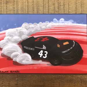 Könnte beinhalten: Ein schwarzes Rennwagen mit der Nummer 43 an der Seite, das auf einer rot-weiß gestreiften Strecke fährt. Das Auto trägt die Aufschrift "#BlackLivesMatter" und "Compassion, Love, Unity". Das Auto hinterlässt eine Spur aus weißem Rauch.