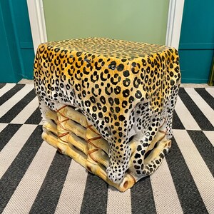 May include: A leopard print stool with a bamboo base. The stool is made of ceramic and has a glossy finish.