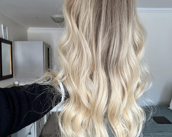 Op de afbeelding: Lang, golvend, lichtblond pruik. De pruik is gestyled in losse golven en heeft een natuurlijk ogende afwerking.