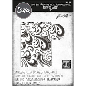 Puede incluir: Una carpeta de repujado en blanco y negro con un patrón de espiral. La carpeta está etiquetada como "Texture Fades" y es parte de la marca Sizzix. Es una carpeta de varios niveles, lo que significa que tiene diferentes niveles de profundidad para crear un efecto más dimensional.