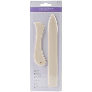 May include: A two-piece scoring tool set in a clear plastic package. The set includes a bone folder and a curved tool, both in a cream color. The package has text that reads "Scoring Tool Set" and "Forever in Time".