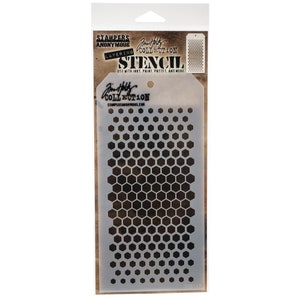 Puede incluir: Una plantilla de plástico blanco con un patrón de panal. La plantilla está empaquetada en una bolsa de plástico transparente con una etiqueta en blanco y negro que dice "Stampers Anonymous Layering Collection Stencil".