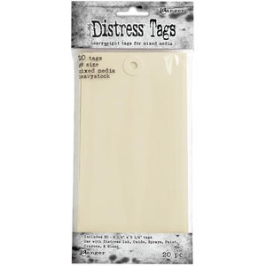May include: A pack of 20 ivory-coloured, heavyweight paper tags, each measuring 15.9 cm by 8.3 cm. The tags are designed for mixed media projects and are ideal for use with Distress Ink, Oxide, Sprays, Paint, Crayons, and Glaze. The pack features the text "Distress Tags" and "Ranger".