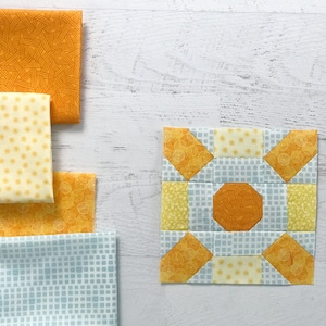 May include: A quilt block with a yellow and blue color scheme. The block is made up of nine smaller squares, each with a different pattern. The center square is a solid yellow, while the surrounding squares are a mix of yellow and blue.
