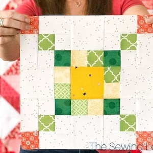 May include: A white quilt block with a yellow, green and white pattern in the centre. The block is surrounded by a white background with small grey dots. The block is labelled "The Sewing Loft" in the bottom right corner.