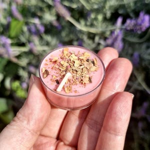 Op de afbeelding: Een roze theelichtje met gedroogde bloemblaadjes en een lont in het midden.