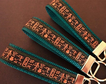 HIEROGLYPH Key Fob. Jacquard fob black, tan, green on teal. Silver nickel hardware. Wristlet. Key chain. 1" wide, Ancient Egypt, African