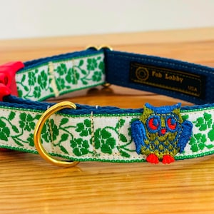 Può includere: Un collare blu per cani con un motivo floreale bianco e un anello in metallo color oro. Il collare presenta un gufo ricamato e il testo "Fab Lobby USA". Il collare ha una fibbia in plastica rossa.
