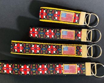 CROSS and FLAG Key Fob Embroidered flag patch red, white, blue, yellow on black. Black or yellow webbing. Silver nickel hardware. 1" wide.