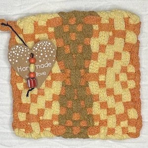 May include: A square, woven hot pad in shades of orange, yellow, and brown. A heart-shaped tag with the words "Handmade with Love" is attached. The tag is decorated with small white dots and colorful beads.