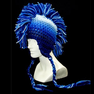 May include: A blue and white crocheted hat with a mohawk style. The hat has a long, braided cord.