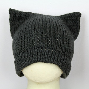 May include: A gray knitted beanie with cat ears. The beanie is made of a soft, warm material and is perfect for keeping your head and ears warm in the winter.