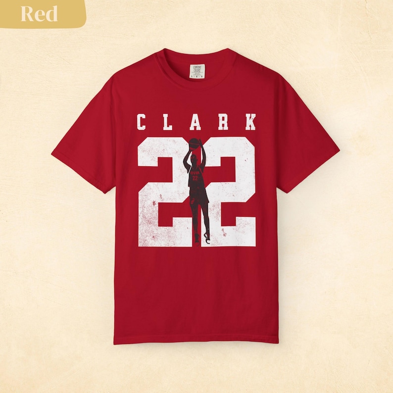 May include: Red t-shirt with the name "CLARK" above the number "22" in white, with a silhouette of a basketball player in the center. The shirt is a solid red color.