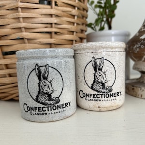 May include: Two antique ceramic jars with a rabbit illustration inside a circle, and the word "Confectionery" printed below. The jars are in shades of gray and off-white, with the text "Glasgow & London" below the word "Confectionery".