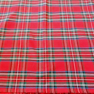May include: Red plaid fabric with a pattern of intersecting lines in white, green, blue, and black. The fabric is folded, creating a textured appearance. The overall theme is textiles.