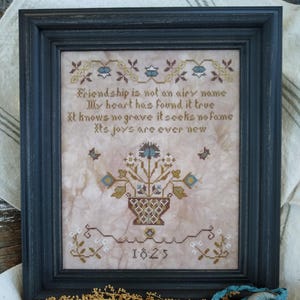 May include: A framed cross-stitch sampler with a floral design and the text "Friendship is not an airy name My heart has found it true It knows no grave it seeks no fame Its joys are ever new 1825".