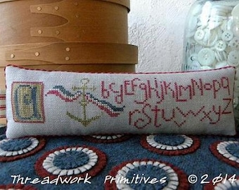 Puede incluir: Una almohada blanca con detalles bordados en rojo, blanco y azul. La almohada presenta un ancla, un alfabeto y el texto "Threadwork Primitives © 2014".