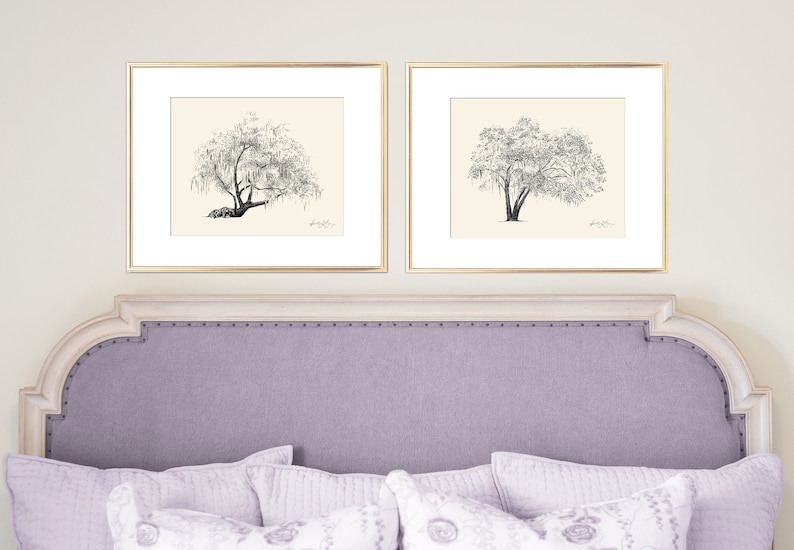 May include: Two black and white drawings of trees in gold frames are hung above a light purple headboard with a tufted design.