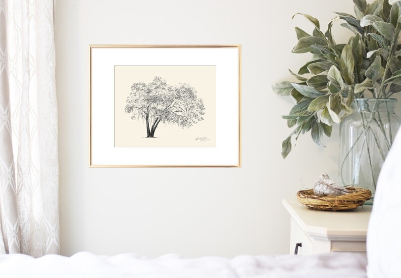 May include: A black and white line drawing of a tree with a thick trunk and many branches. The drawing is framed in a gold frame and hung on a white wall.