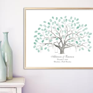 May include: A framed print featuring a tree design with teal-colored fingerprint leaves. The tree has swings hanging from its branches. The names "Adrienne & Emerson" and the date December 4, 2015, are printed below the tree.