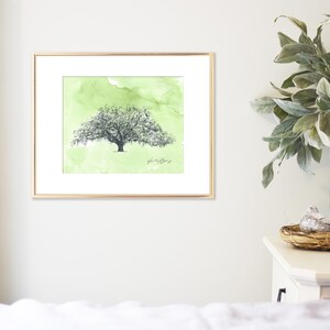 May include: A framed watercolor painting of a large tree with green foliage and a light green background. The text "plant a tree" is written in cursive at the bottom of the painting.