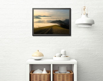 May include: A framed landscape photograph shows a mountain ridge rising from fog. The sky shifts from a golden sunrise to a soft blue. A path crosses the grassy ridge, drawing the viewer's eye across the scene.