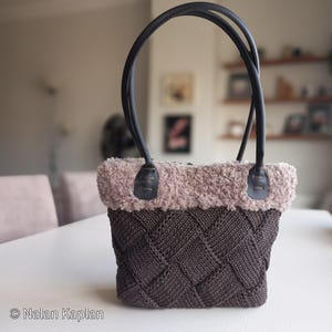 May include: A brown knitted tote bag with a faux fur trim and black leather handles. The bag has a woven pattern and is made with a soft, cosy fabric.