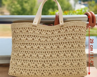 May include: A beige woven tote bag with cream-colored handles. The bag has an openwork design and measures 16.5 inches wide and 11.4 inches high. The bag is made of a natural fiber material.