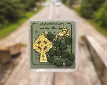 May include: A green and gold Irish pocket rosary with a Celtic cross and an Irish blessing card. The card reads "An Irish Blessing" and includes the text "May the road rise to meet you..."
