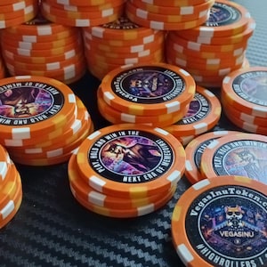 Può includere: Gettoni da poker arancioni e bianchi con un logo Vegas Inu Token e il testo "Hold and Win in the Next Era of Memecoins" e "High Rollers | 1 Suit".