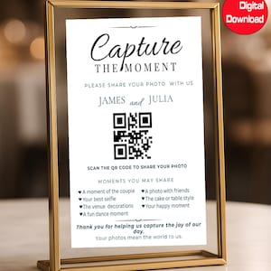 以下が含まれることがあります： 「Capture the Moment」の文字とQRコードが入った金色のフレームのサイン。サインには「James and Julia」の名前が記載されており、ゲストに写真の共有を促しています。CanvaとDigital Downloadのロゴが見えます。