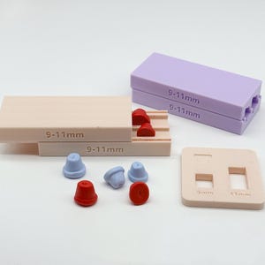 May include: A set of silicone molds for crafting, including a rectangular beige mold with 9-11mm text, a rectangular lavender mold with 9-11mm text, and a square beige sizing guide with 9mm and 11mm cutouts, alongside small red and blue conical shapes.
