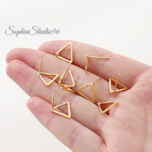 May include: A collection of gold-colored metal stud earrings, each shaped as an open triangle. The earrings feature a thin wire frame and a straight post backing, arranged in a cluster. The text SophiaStudio96 is visible in the upper left corner.