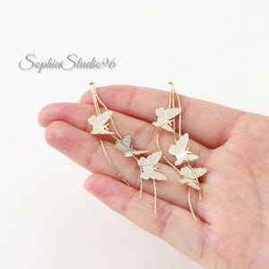 May include: A pair of gold-toned dangling earrings featuring multiple butterfly charms attached to thin, textured chains. The earrings have a delicate, layered design with several butterflies suspended at varying lengths along the metallic chains.