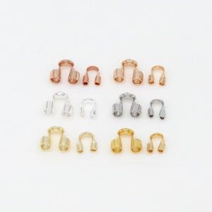 May include: An assortment of metal jewelry findings in copper, silver, and gold tones. The findings are in a U-shape with two cylindrical posts on each side. The findings are arranged in rows on a white background.