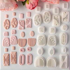 May include: A collection of light pink clay earring components featuring various geometric textures and shapes, alongside a set of white plastic cutters used to create these designs, including ovals, rectangles, and semi-circles with line patterns.