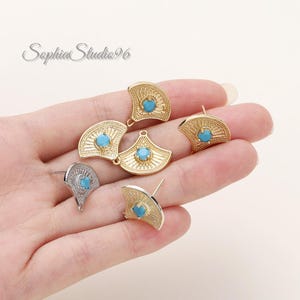 May include: A collection of fan-shaped earring components featuring a central round turquoise-colored stone. The pieces are finished in gold and silver tones, with textured radiating lines extending from the center to the curved outer edge.