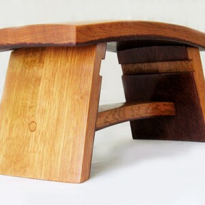 May include: A wooden stool made from repurposed wine barrels. The stool has a curved top and a unique, asymmetrical design.