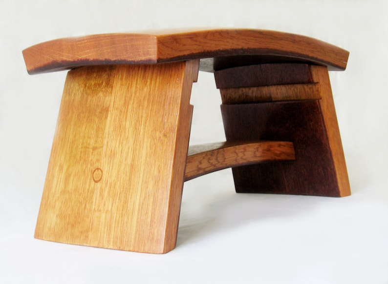 May include: A wooden stool made from repurposed wine barrels. The stool has a curved top and a unique, asymmetrical design.