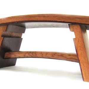 May include: A wooden stool with a curved top and a unique design. The stool is made of dark brown wood and has a natural finish.