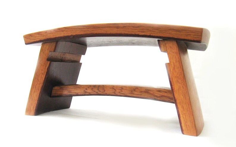 May include: A wooden stool with a curved top and a unique design. The stool is made of dark brown wood and has a natural finish.