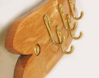 May include: Wooden key holder with a natural finish and four brass hooks. The key holder is shaped like a fish.