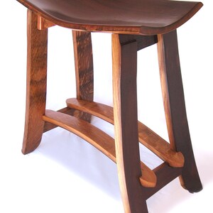 May include: A dark brown wooden stool with a curved seat and a unique, open-frame design. The stool has two horizontal supports and a curved, open-frame base.