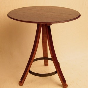 May include: A round wooden table with a dark brown top and a tripod base made of wood with a metal ring around the bottom.