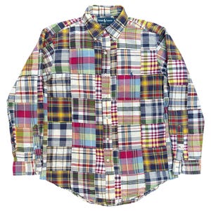 May include: A long-sleeved button-down shirt with a patchwork design. The shirt features a variety of plaid patterns in colors like red, blue, yellow, and green. The collar has a label that reads "Ralph Lauren".
