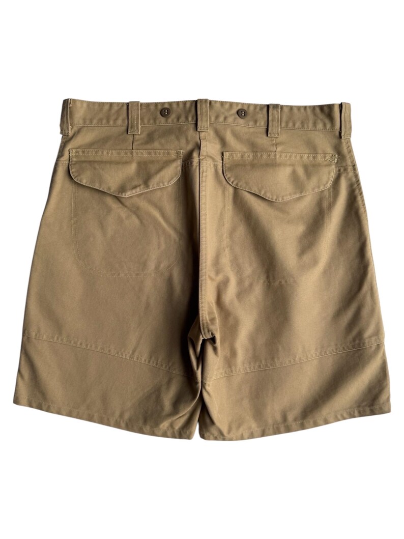 Puede incluir: Pantalones cortos color caqui con dos bolsillos traseros y cierre de bot&oacute;n. Los pantalones cortos tienen un dise&ntilde;o cl&aacute;sico con un ajuste a medida. La tela parece ser una mezcla de algod&oacute;n duradera, adecuada para ropa casual. Los pantalones cortos tienen trabillas y cierre de bot&oacute;n.