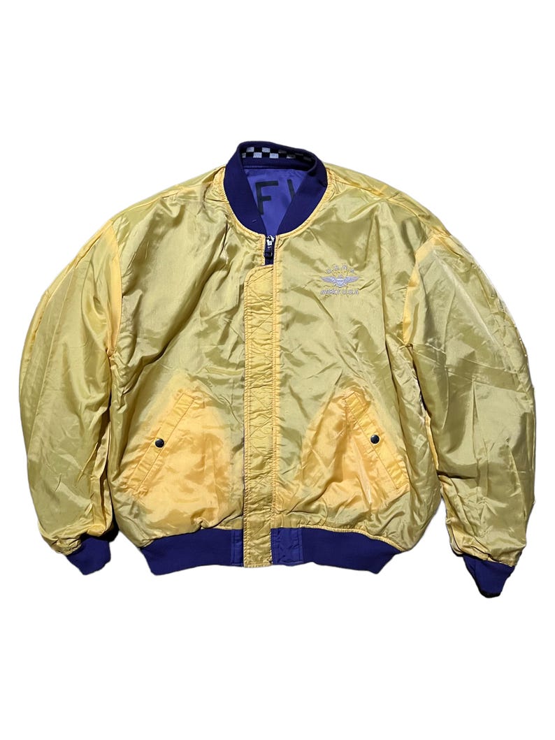 May include: Yellow bomber jacket with a blue collar, cuffs, and hem. The jacket has a zipper closure and two front pockets. The interior is a contrasting blue color. The jacket has the text "FY" and a logo on the chest.