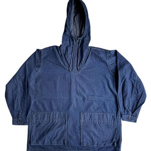 May include: A blue denim hooded jacket with a half-zip closure and two large front pockets. The jacket has long sleeves with buttoned cuffs. The hood is lined with a lighter shade of blue denim.
