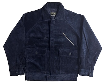 Puede incluir: Chaqueta de pana azul marino con cuello, dos bolsillos delanteros y un bolsillo en el pecho con cremallera. La chaqueta tiene botones y puños y dobladillo acanalados. Una prenda de abrigo clásica.
